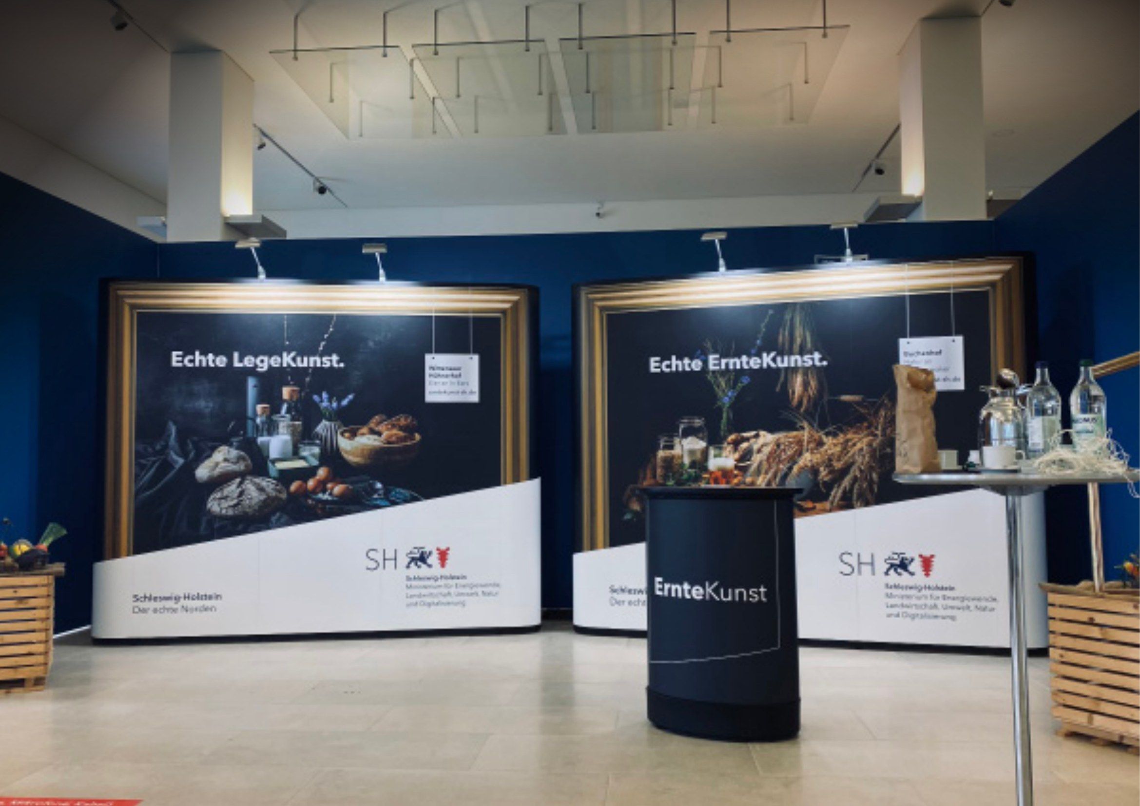 Zwei großformatige Kampagnenmotive im Goldrahmen in einem Ausstellungsfoyer